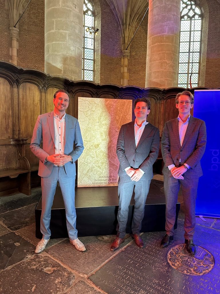 Wethouder Christian Schouten (links) en twee betrokken projectpartners bij de onthulling van een houten stadskaart tijdens de start van de bouw van Buitenvaart in de Grote Sint Laurens Kerk.